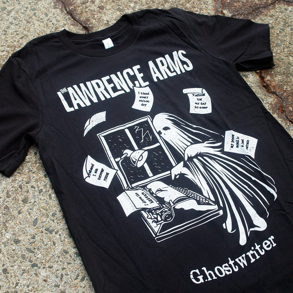 close up Photo of a black tshirt against a grey asphalt speckled background. The tshirt says the lawrence arms across the chest in white text. Below that is a graphic of a ghost standing near a window. There is a typewriter and a lamp over the typewriter. The ghost is typing something, and pieces of paper are arranged around the ghost in the air in a circular shape. Below the graphic in white text reads "ghostwriter".